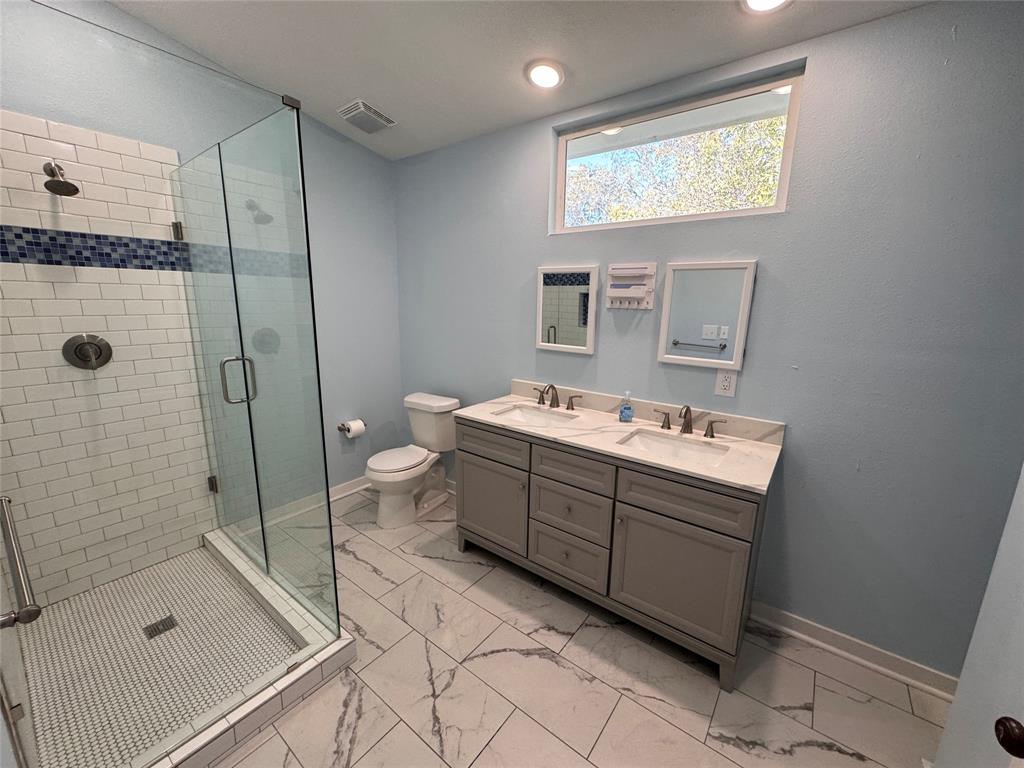 2547 Sharon Street Dallas, TX 75211 - Photo 18 of 22 a bathroom with a double vanity sink toilet mirror and shower