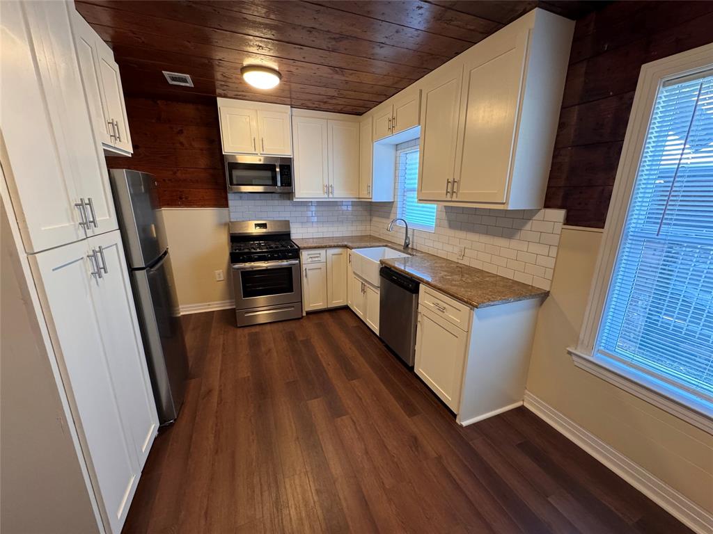 2547 Sharon Street Dallas, TX 75211 - Photo 4 of 22 a kitchen with stainless steel appliances granite countertop wooden floors a stove and a refrigerator