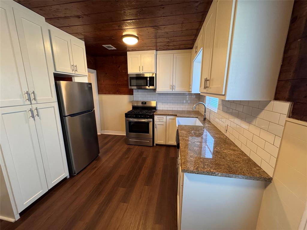 2547 Sharon Street Dallas, TX 75211 - Photo 7 of 22 a kitchen with stainless steel appliances granite countertop a refrigerator a sink dishwasher a stove and white countertops with wooden floor