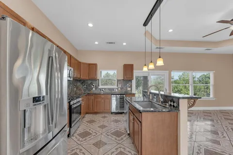 a kitchen with stainless steel appliances granite countertop a refrigerator a stove a sink and a oven