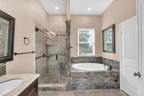a bathroom with a granite countertop sink a large mirror and a bathtub
