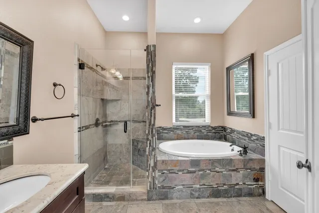 a bathroom with a granite countertop sink a large mirror and a bathtub