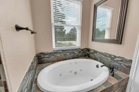 a spacious bathroom with a granite countertop sink mirror and bathtub