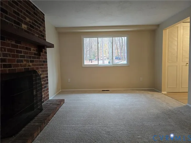 a view of an empty room with a fireplace and a window