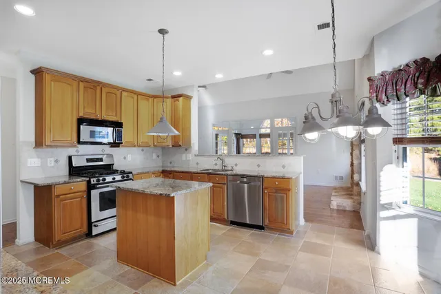 a kitchen with stainless steel appliances granite countertop a stove top oven a sink a dining table and chairs