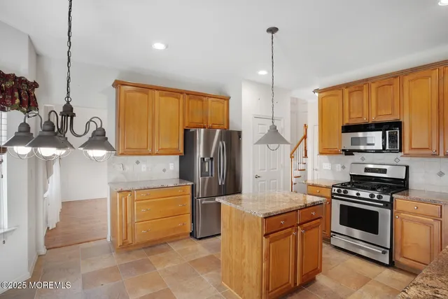 a kitchen with stainless steel appliances granite countertop a stove a sink and a refrigerator