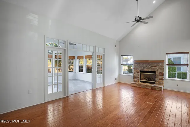 an empty room with wooden floor fireplace and windows