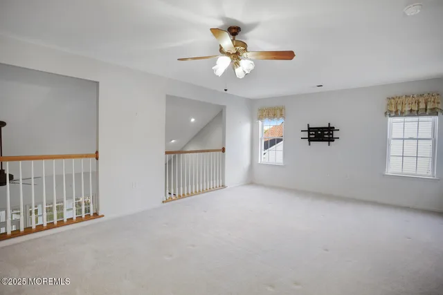 en empty room with windows and ceiling fan