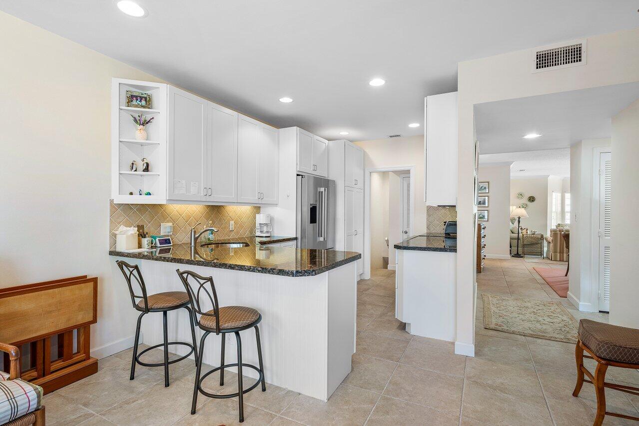 5900 Old Ocean Boulevard, Unit C6 Ocean Ridge, FL 33435 - Photo 20 of 21 a kitchen with stainless steel appliances kitchen island granite countertop a table chairs and a refrigerator