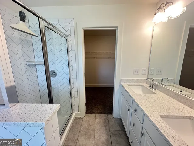 a bathroom with a granite countertop sink a mirror and a shower