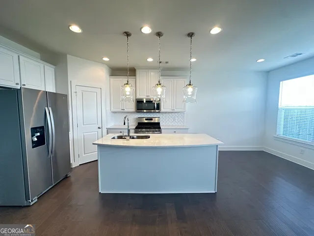 a kitchen with kitchen island a stove a refrigerator a sink and a oven with wooden floor