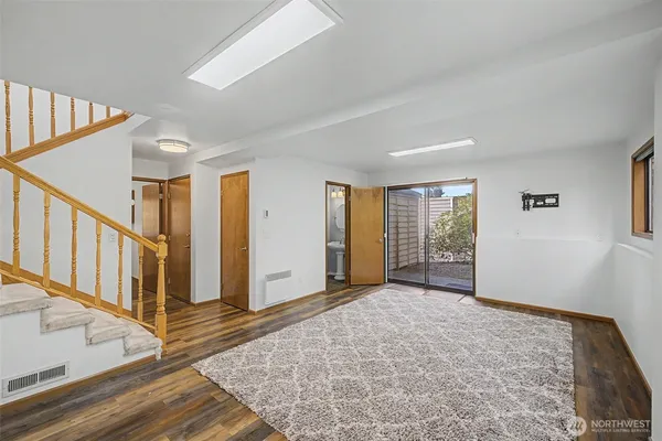 a view of an empty room with wooden floor and stairs