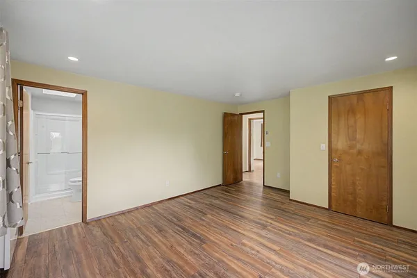 a view of an empty room with wooden floor and closet
