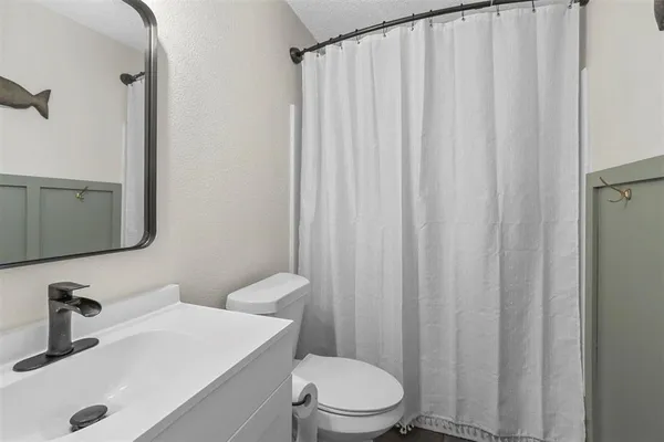 a bathroom with a sink a toilet and shower curtain