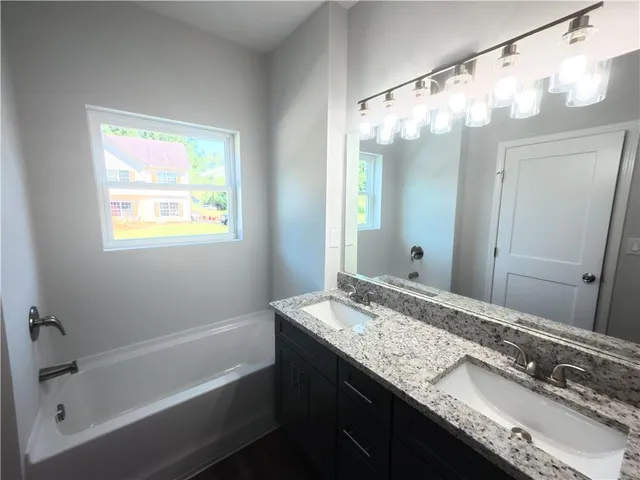 a bathroom with a granite countertop sink mirror and a bath tub