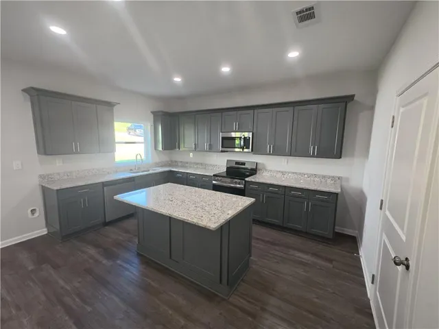 a kitchen with a stove a sink a microwave a center island and a window