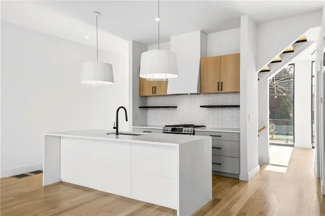 a kitchen with stainless steel appliances granite countertop a sink a stove and a wooden floors