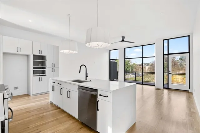 a open kitchen with stainless steel appliances granite countertop a stove and a white refrigerator with wooden floor