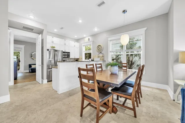 a kitchen with stainless steel appliances kitchen island granite countertop a dining table chairs and refrigerator
