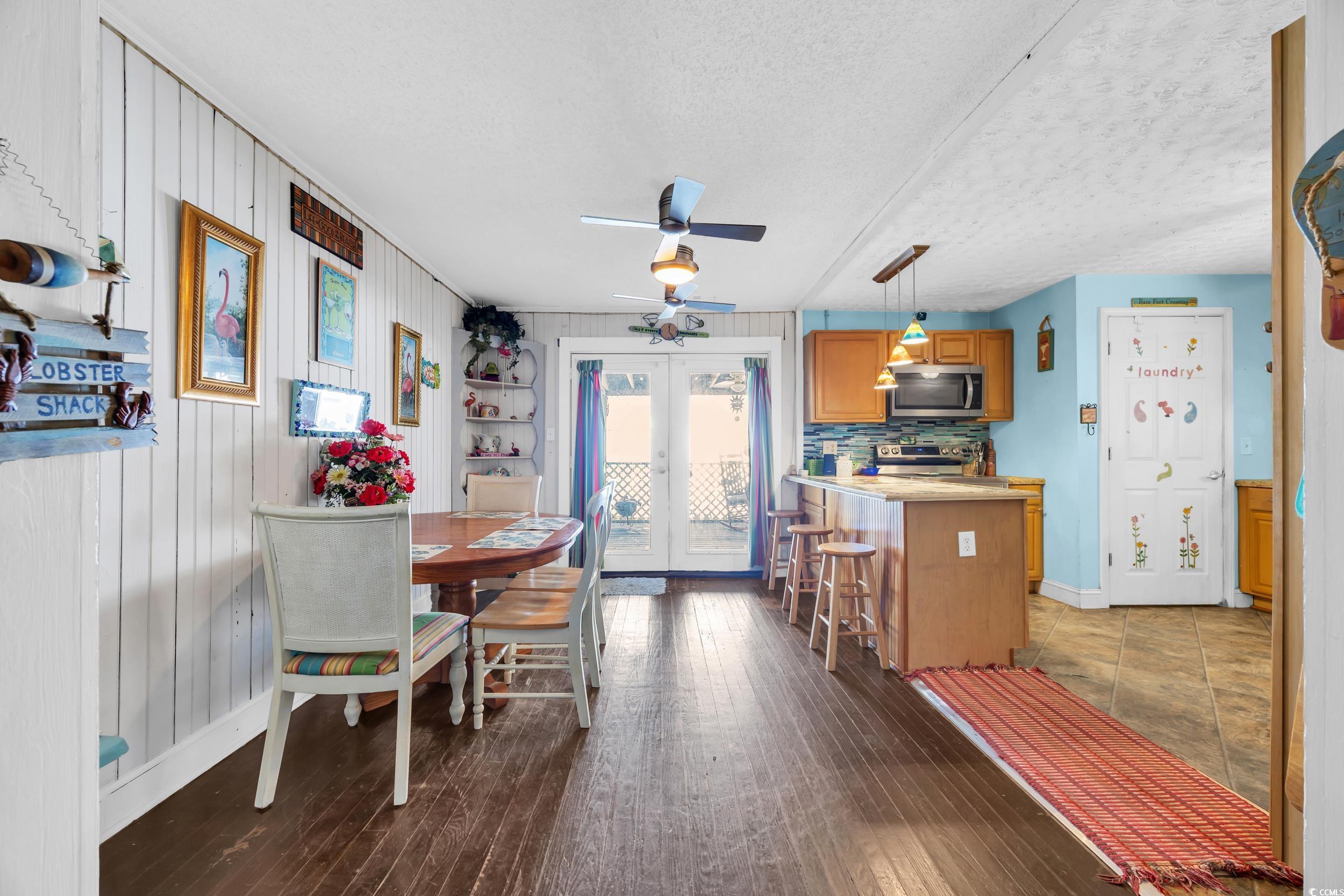 1616 Perrin Drive North Myrtle Beach, SC 29582 - Photo 11 of 40 Dining space featuring a textured ceiling, french doors, dark wood-style flooring, a ceiling fan, and wood walls