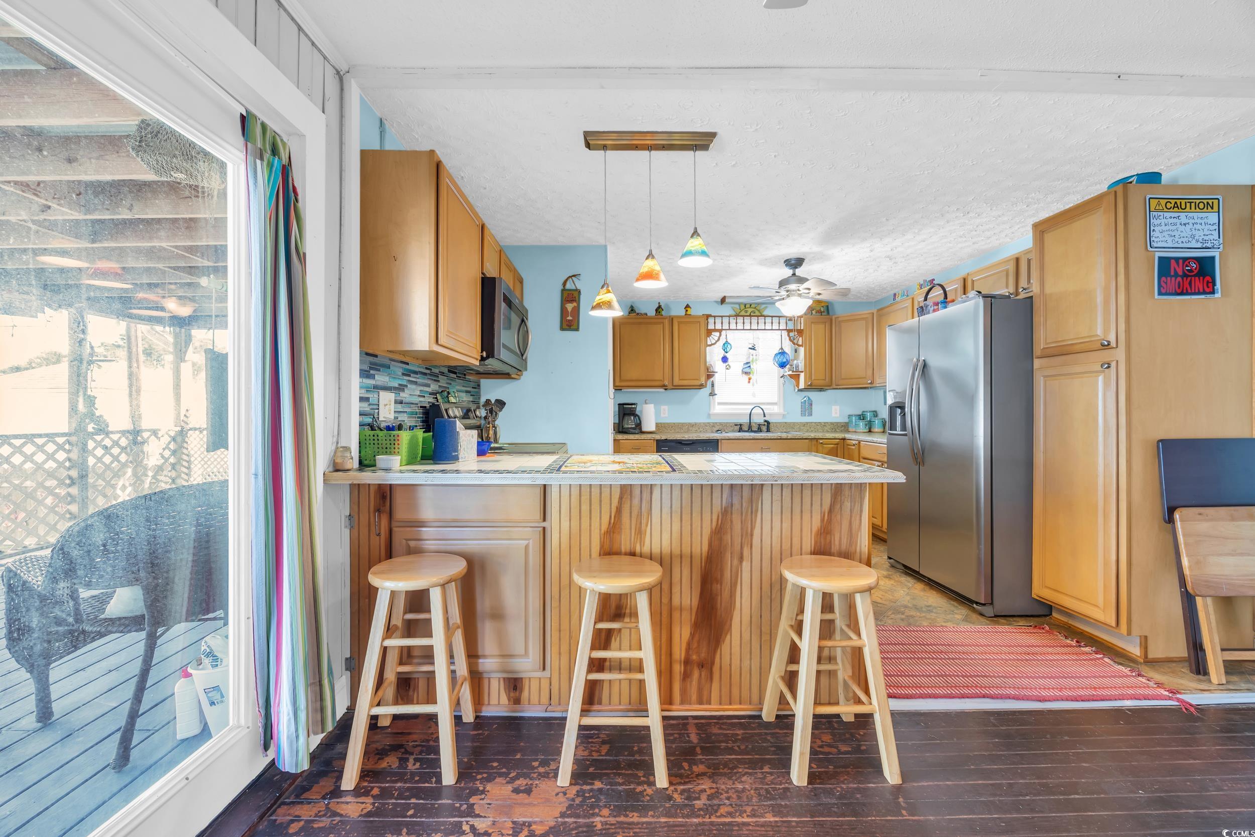 1616 Perrin Drive North Myrtle Beach, SC 29582 - Photo 14 of 40 Kitchen with a peninsula, stainless steel appliances, a breakfast bar, dark wood-style flooring, and decorative light fixtures