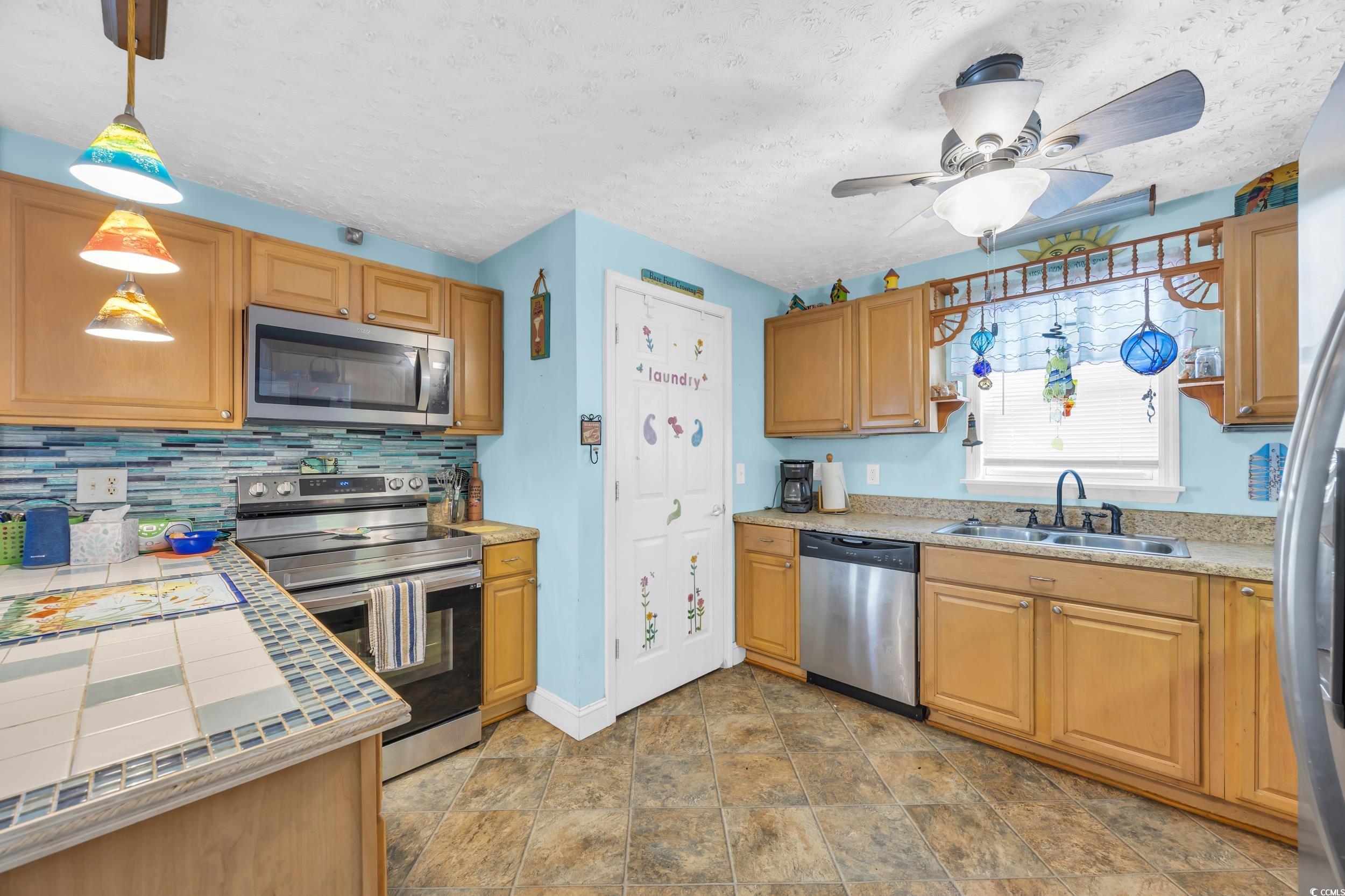 1616 Perrin Drive North Myrtle Beach, SC 29582 - Photo 15 of 40 Kitchen featuring appliances with stainless steel finishes, decorative light fixtures, decorative backsplash, a textured ceiling, and a ceiling fan