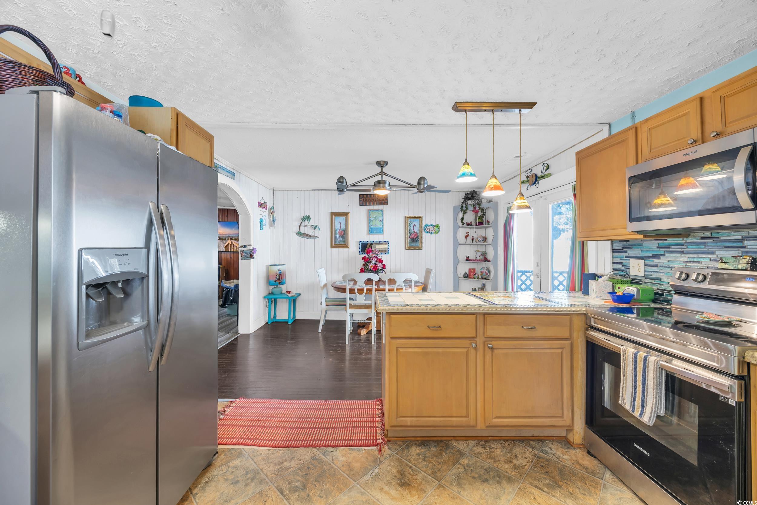 1616 Perrin Drive North Myrtle Beach, SC 29582 - Photo 17 of 40 Kitchen featuring appliances with stainless steel finishes, a textured ceiling, arched walkways, decorative light fixtures, and brown cabinets