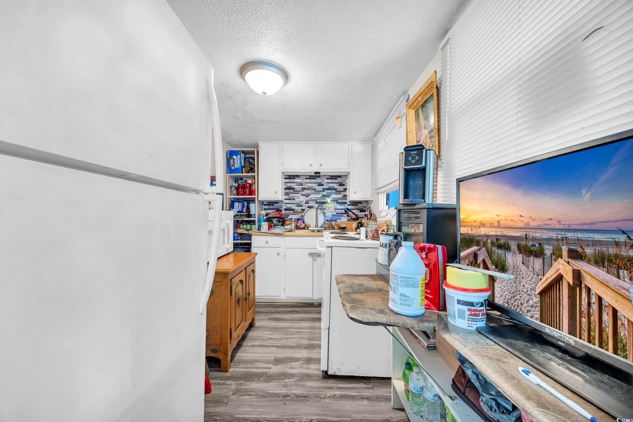 1616 Perrin Drive North Myrtle Beach, SC 29582 - Photo 27 of 40 Kitchen featuring freestanding refrigerator, decorative backsplash, a textured ceiling, white cabinets, and light countertops