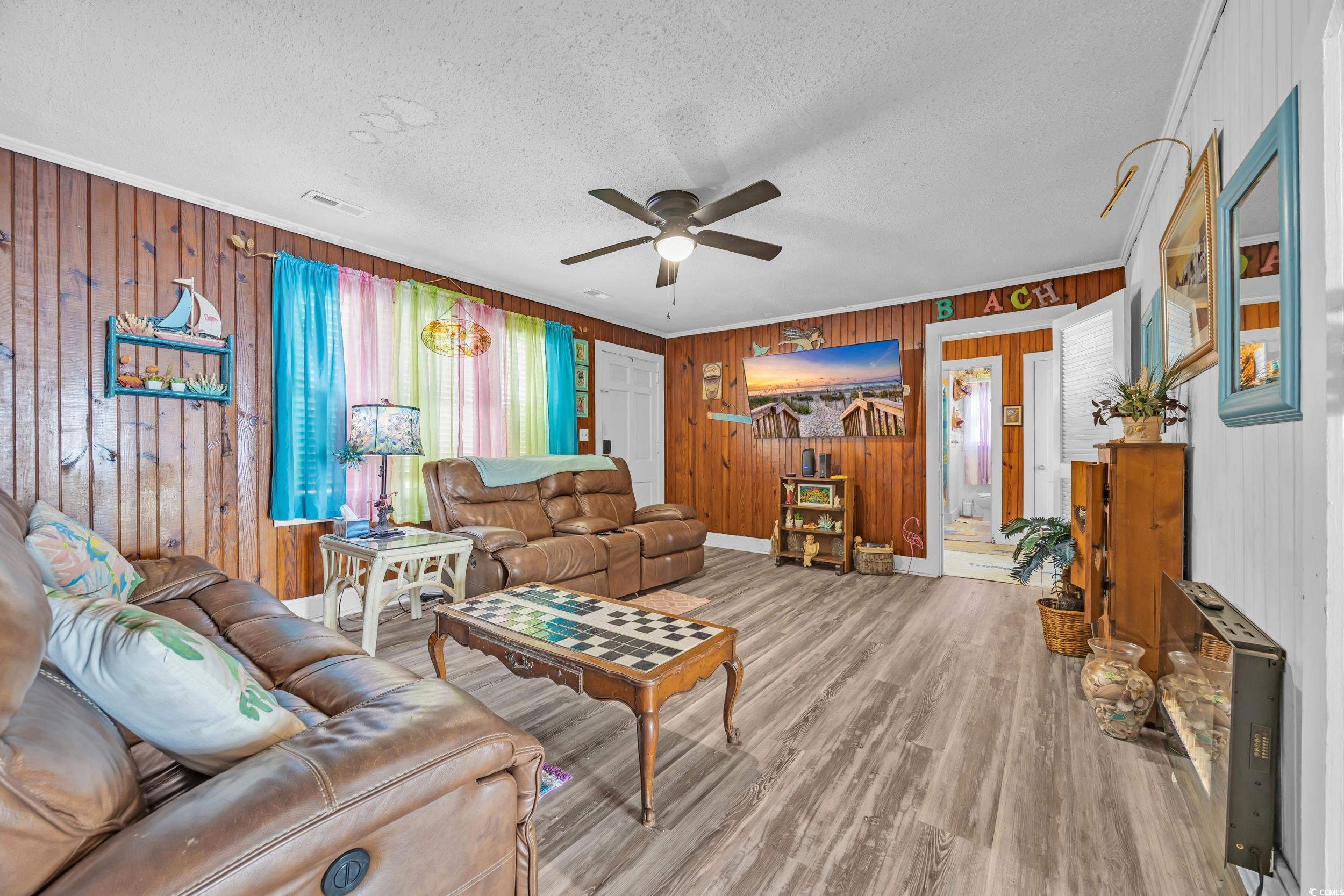 1616 Perrin Drive North Myrtle Beach, SC 29582 - Photo 4 of 40 Living room with wood walls, wood finished floors, a textured ceiling, a ceiling fan, and ornamental molding