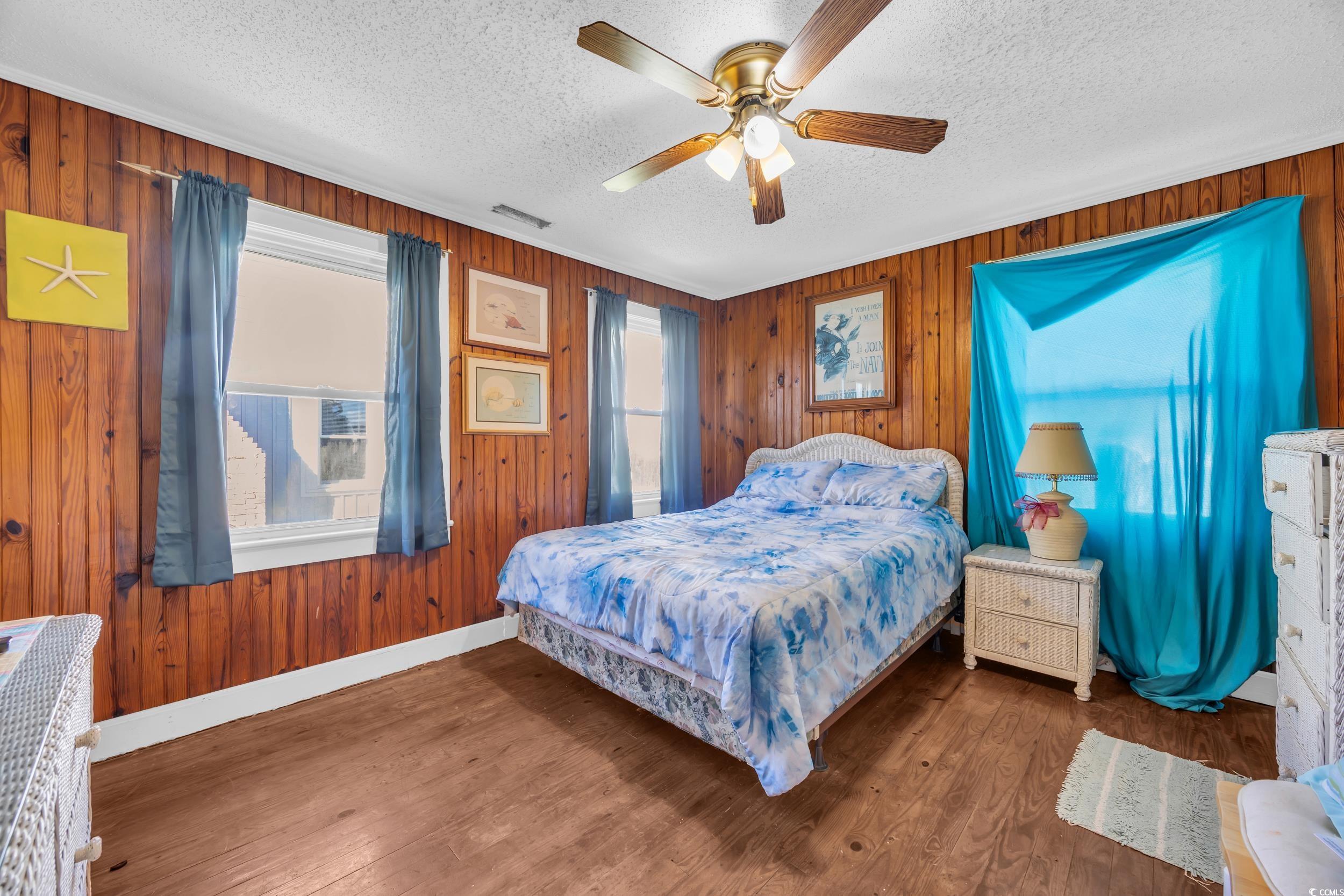 1616 Perrin Drive North Myrtle Beach, SC 29582 - Photo 8 of 40 Bedroom featuring wood walls, a ceiling fan, wood finished floors, and a textured ceiling