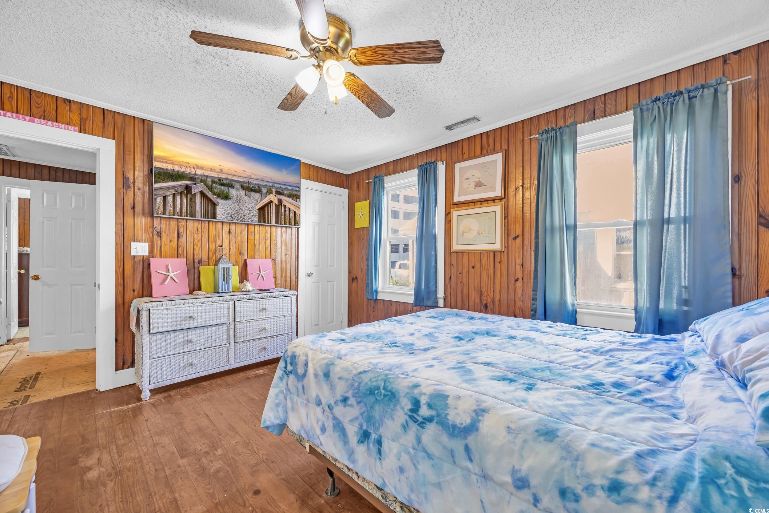 1616 Perrin Drive North Myrtle Beach, SC 29582 - Photo 9 of 40 Bedroom featuring wooden walls, wood finished floors, a ceiling fan, and a textured ceiling