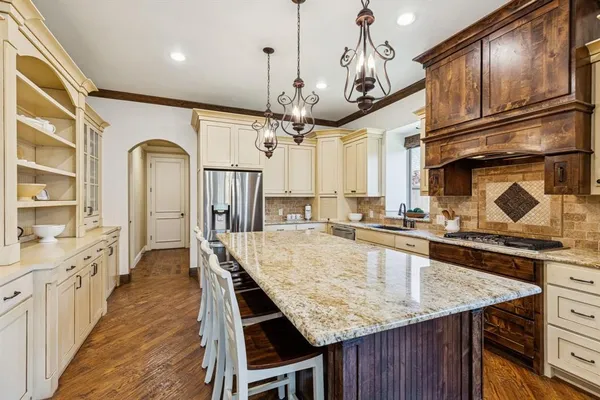 a kitchen with stainless steel appliances granite countertop a kitchen island a stove and a wooden floors