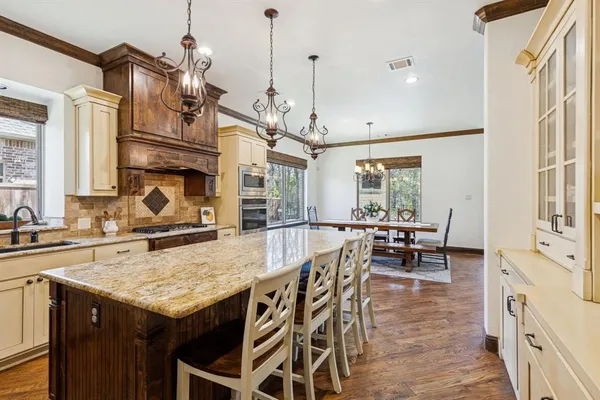 a kitchen with granite countertop a stove a sink a dining table and chairs