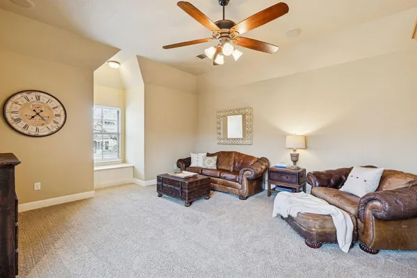 a living room with furniture a large window and a ceiling fan