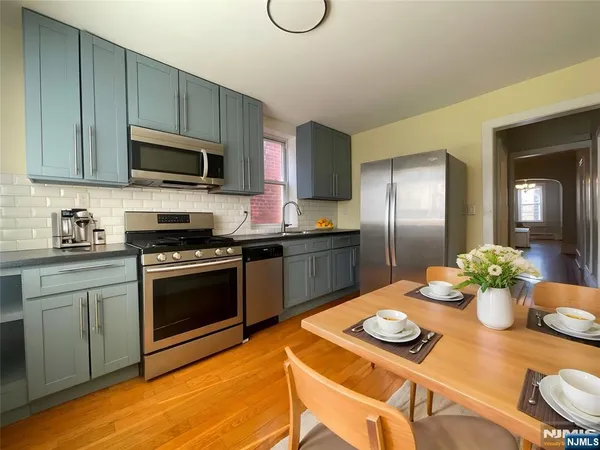 a kitchen with stainless steel appliances granite countertop a stove a sink dishwasher a dining table and chairs with wooden floor