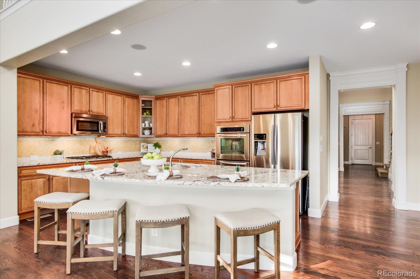 470 Maplehurst Drive Highlands Ranch, CO 80126 - Photo 10 of 40 a kitchen with stainless steel appliances granite countertop a stove top oven a refrigerator a sink and a dining table with white cabinets