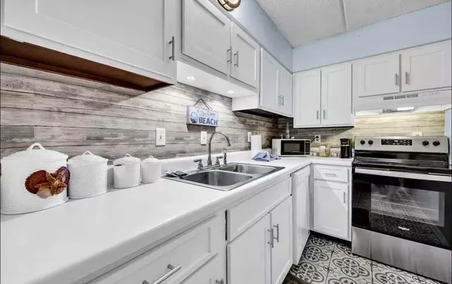 a kitchen with white cabinets and sink