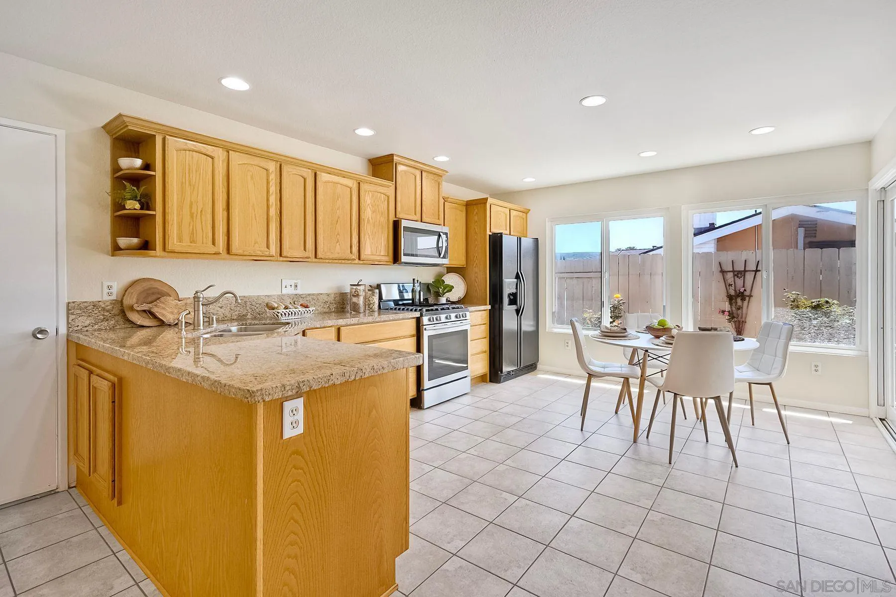 13440 Montego Drive Poway, CA 92064 - Photo 9 of 35 a kitchen with granite countertop a sink a stove cabinets dining table and chairs