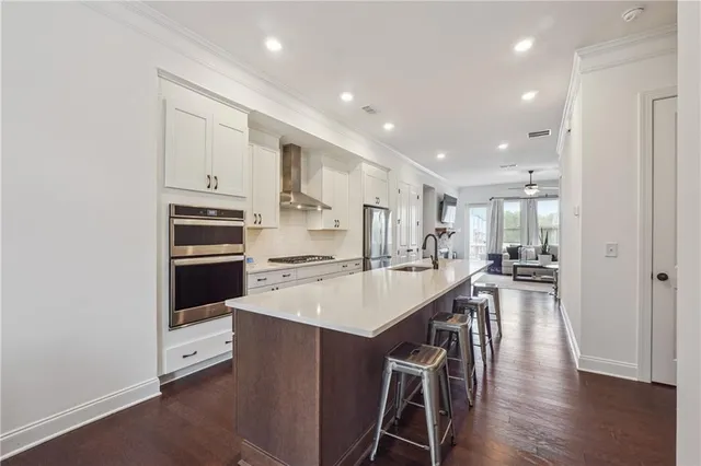 a kitchen with stainless steel appliances a refrigerator a stove and white cabinets with wooden floor