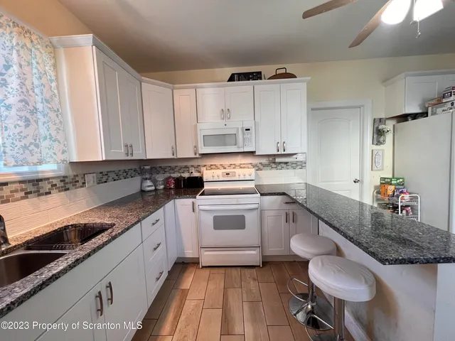 a kitchen with granite countertop white cabinets and white appliances