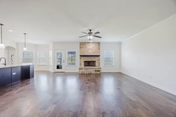 a view of a living room a kitchen with furniture a fireplace and wooden floor