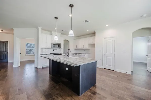 a kitchen with stainless steel appliances granite countertop a sink a stove and a wooden floors