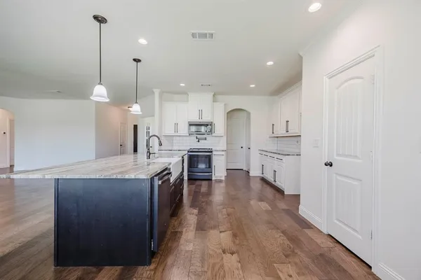 a kitchen with kitchen island a sink stainless steel appliances and cabinets