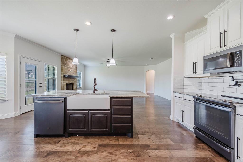 105 Kathy Stephens Avenue Springtown, TX 76082 - Photo 30 of 40 a large kitchen with stainless steel appliances granite countertop a stove a sink and a wooden floors