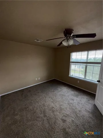 an empty room with a ceiling fan and a window