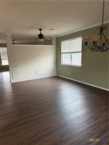 an empty room with wooden floor cabinet and windows