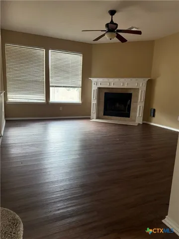 an empty room with wooden floor fireplace and windows
