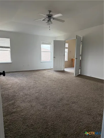 a view of a big room with windows and chandelier fan