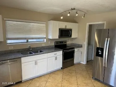 a kitchen with granite countertop a sink stainless steel appliances and cabinets