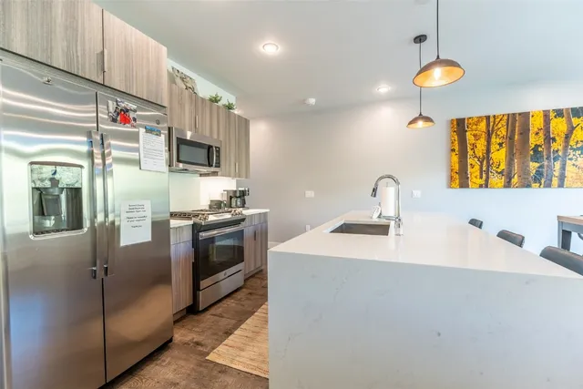 a kitchen with stainless steel appliances granite countertop a sink a stove and a refrigerator